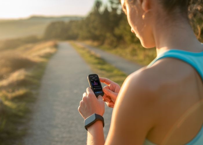 Runner analyzing running data on fitness tracker, showing average running times and pace.