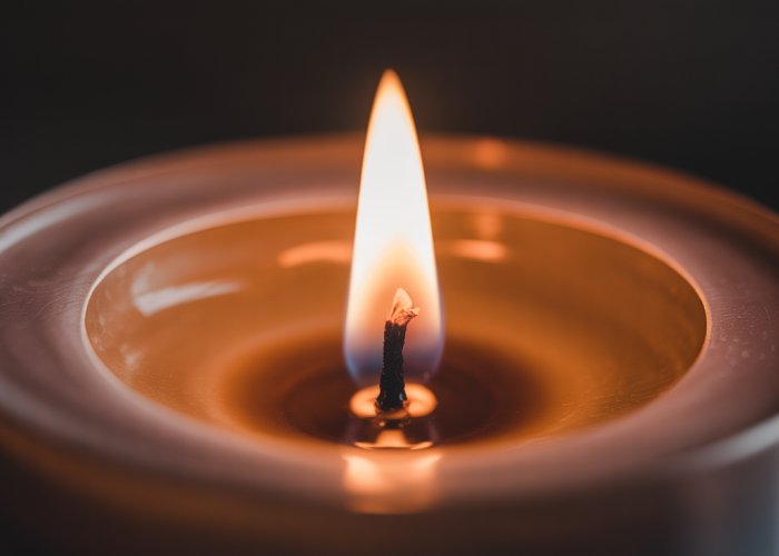 Close-up of a candle flame flickering in the darkness.