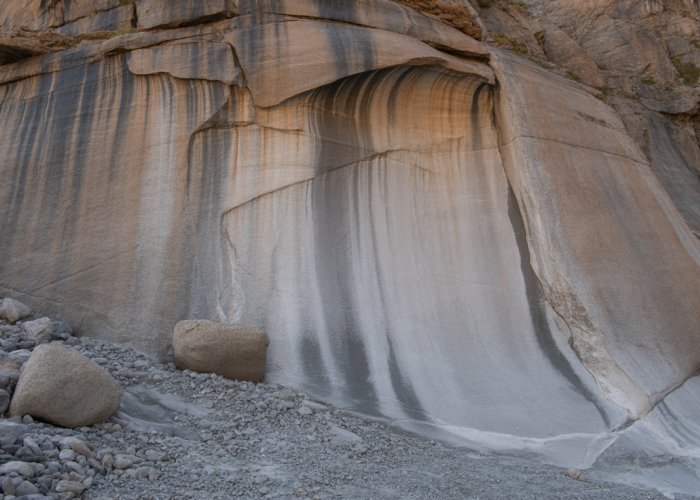 Rock face showing signs of mechanical weathering, including cracks, exfoliation, and variations in texture.