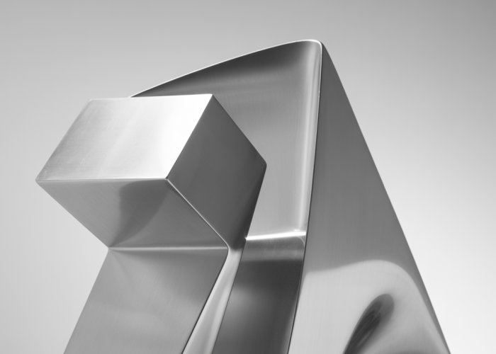 Minimalist steel sculpture with geometric shapes and polished surface.