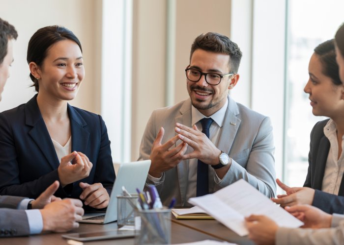 Professionals in a meeting using paralinguistic cues, like changes in tone and facial expressions, to communicate.