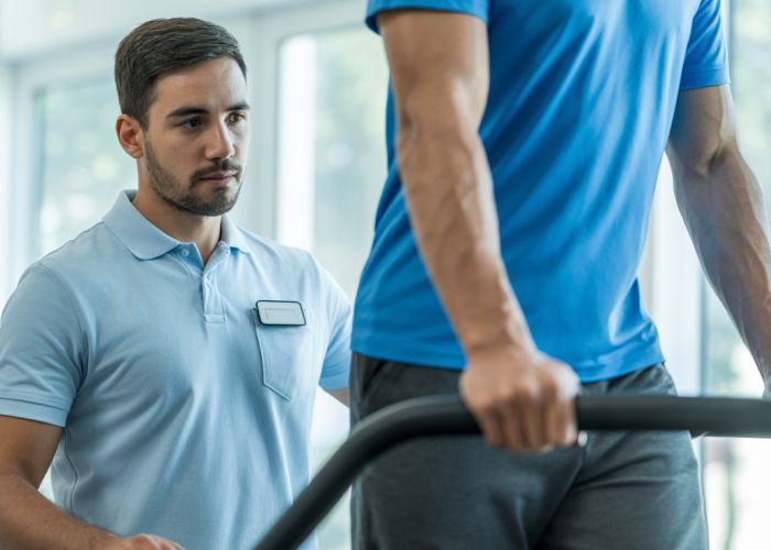 Physical therapist assessing a patient's gait on a treadmill to identify walking asymmetry.