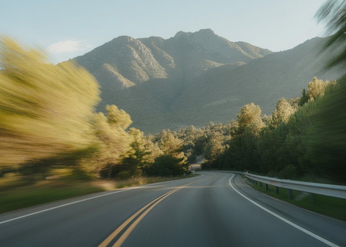Winding road with foreground trees blurring and distant mountains appearing still, illustrating the motion parallax effect.