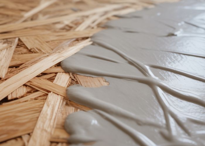 Close-up of OSB showing primer applied to half the surface.