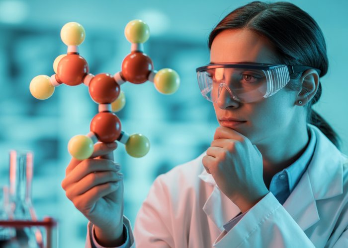 Chemist studying a T-shaped molecule model in a lab.