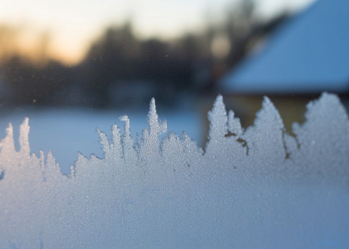 Frost pattern on windowpane caused by indoor humidity in winter.